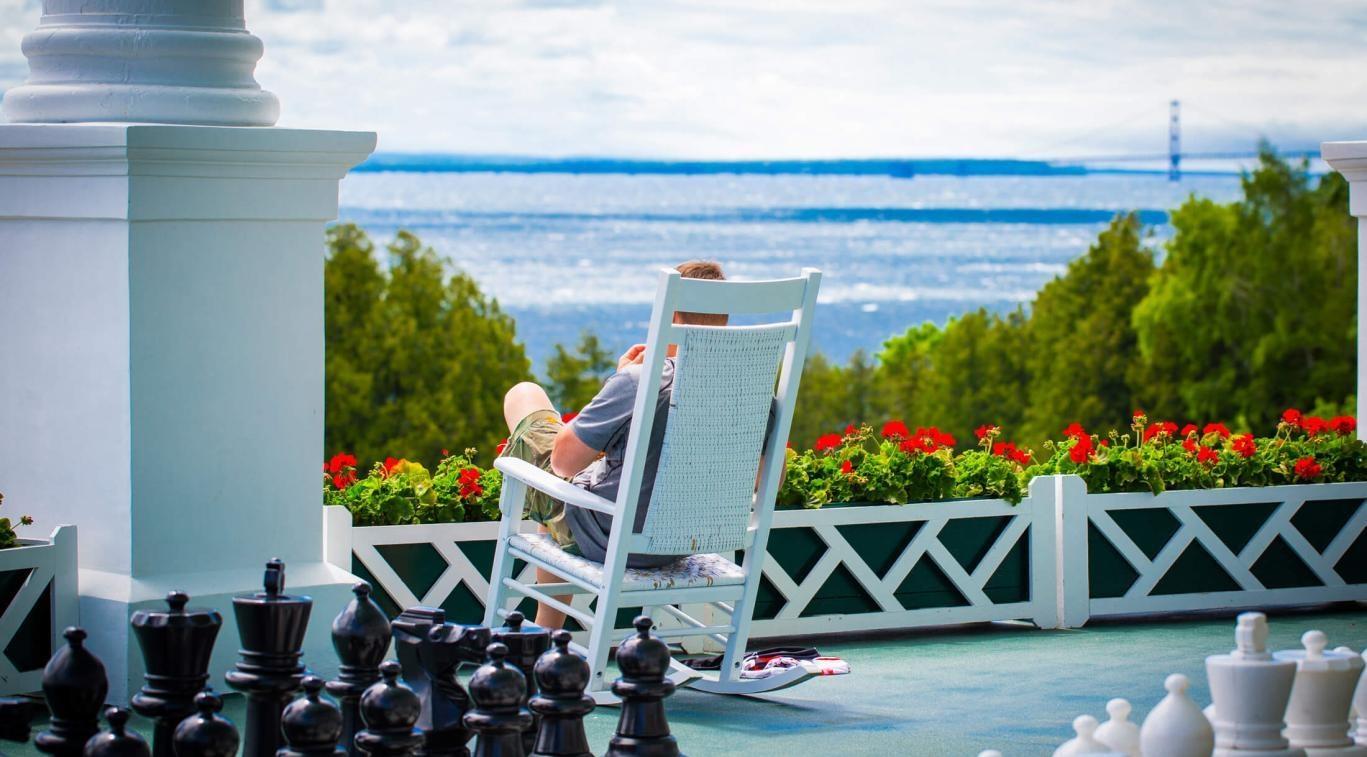 Man enjoying one of the rocking chairs lined along the Grand Hotel porch overlooking Mackinac Island