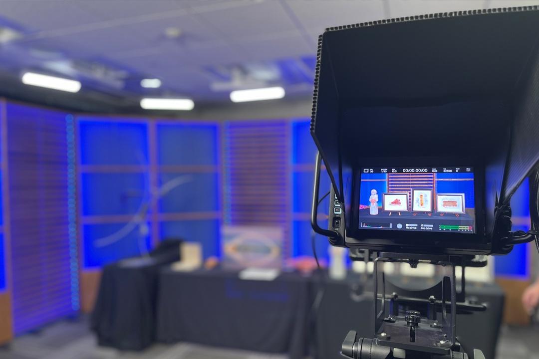 A behind-the-scenes view of a TV studio with auction items sitting on a table