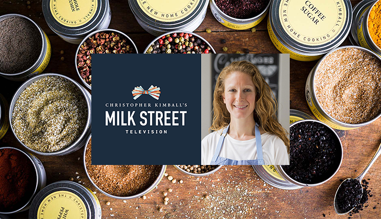Rosemary Gill, the Director of Education for Christopher Kimball's Milk Street in front of an image containing tins of  spices