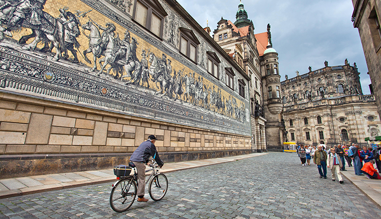 Man cycling down a coble stone street in a German city.