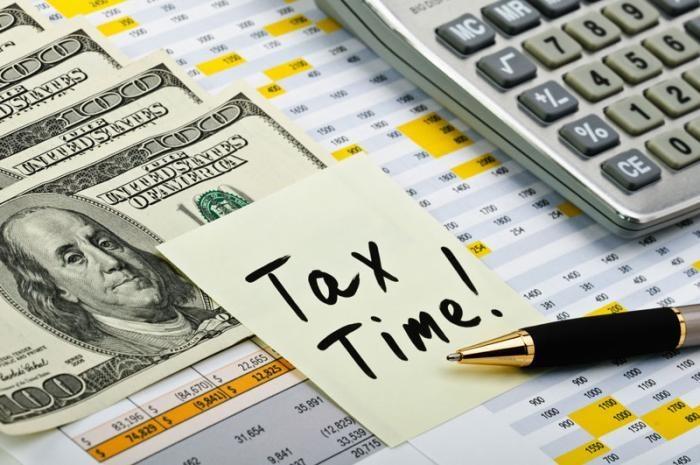 Image of $100 bills, a calculator, spreadsheets, and a pen next to a note that reads "Tax Time!"