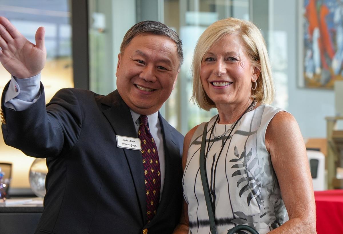 Two smiling people waving at the camera