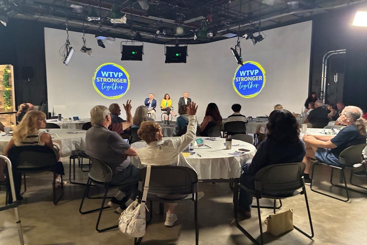 Volunteers sit at round tables in WTVP's studio