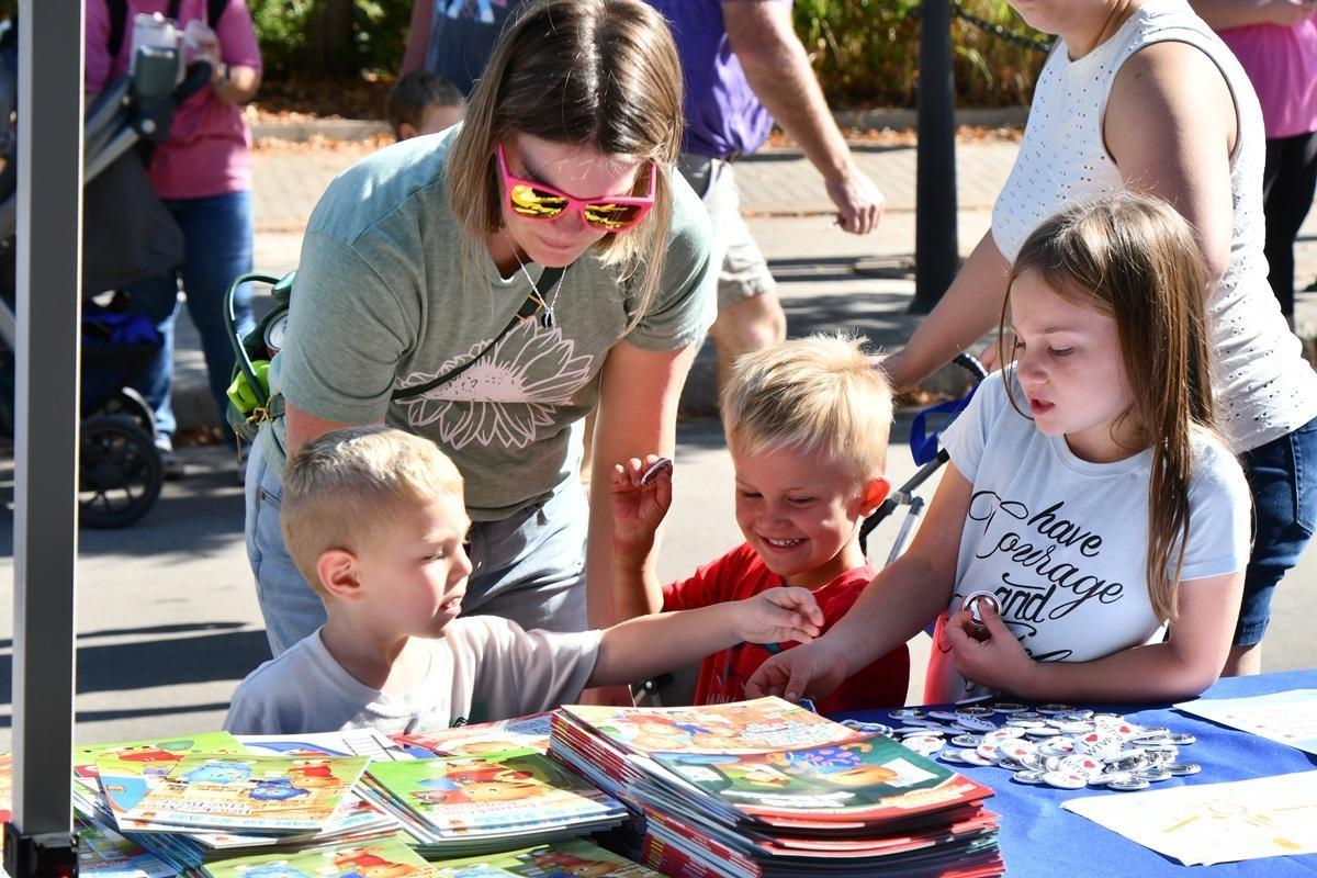 A mom and three kids look at Daniel Tiger books laid out on a table