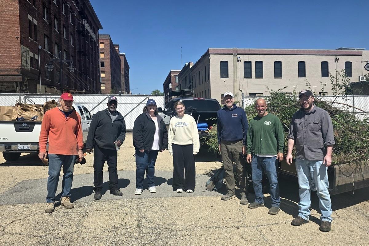 Seven volunteers stand in a semicircle before doing yard work