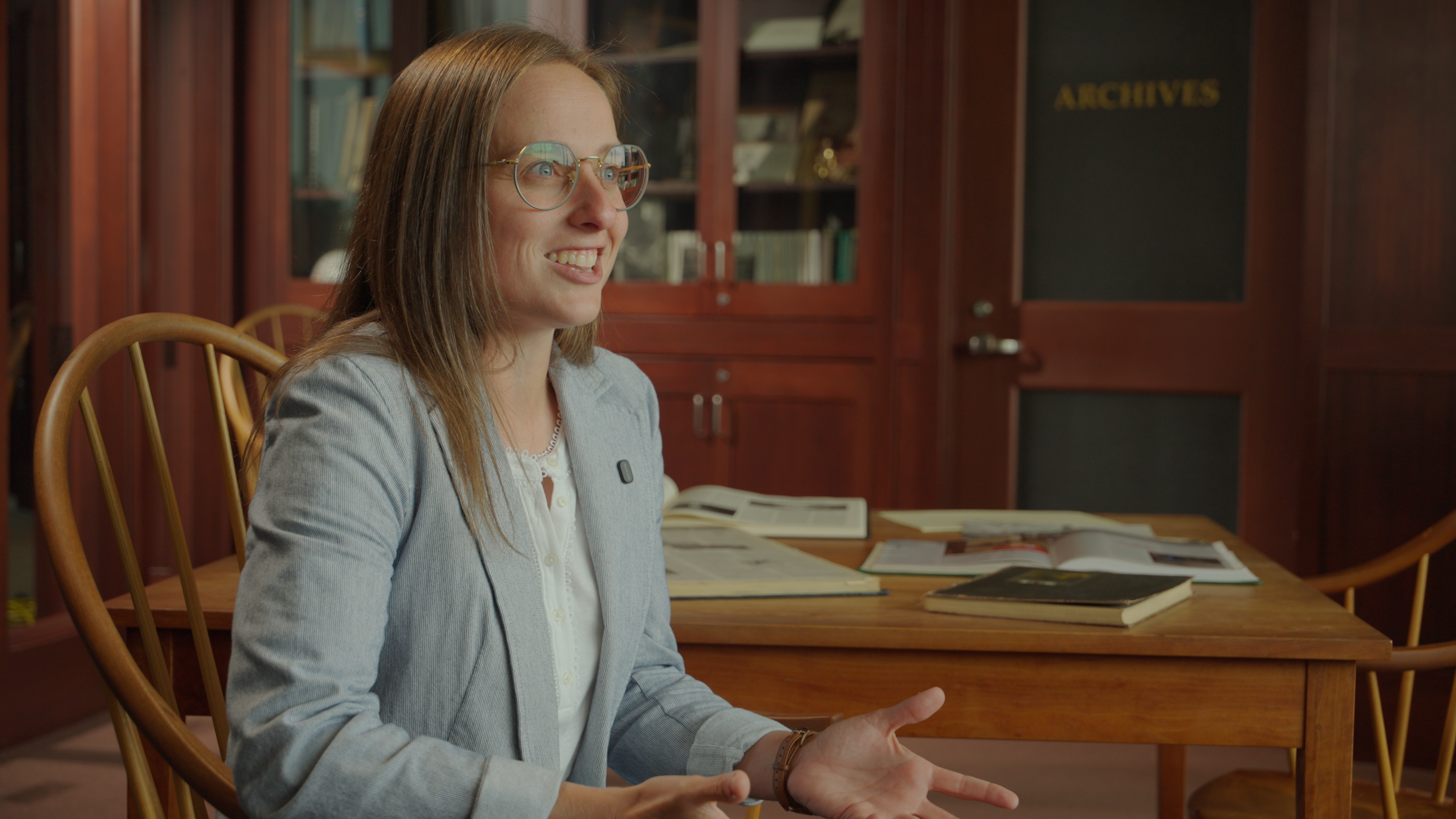 The profile of a young woman wearing glasses sitting in the Archives room of Illinois Wesleyan University