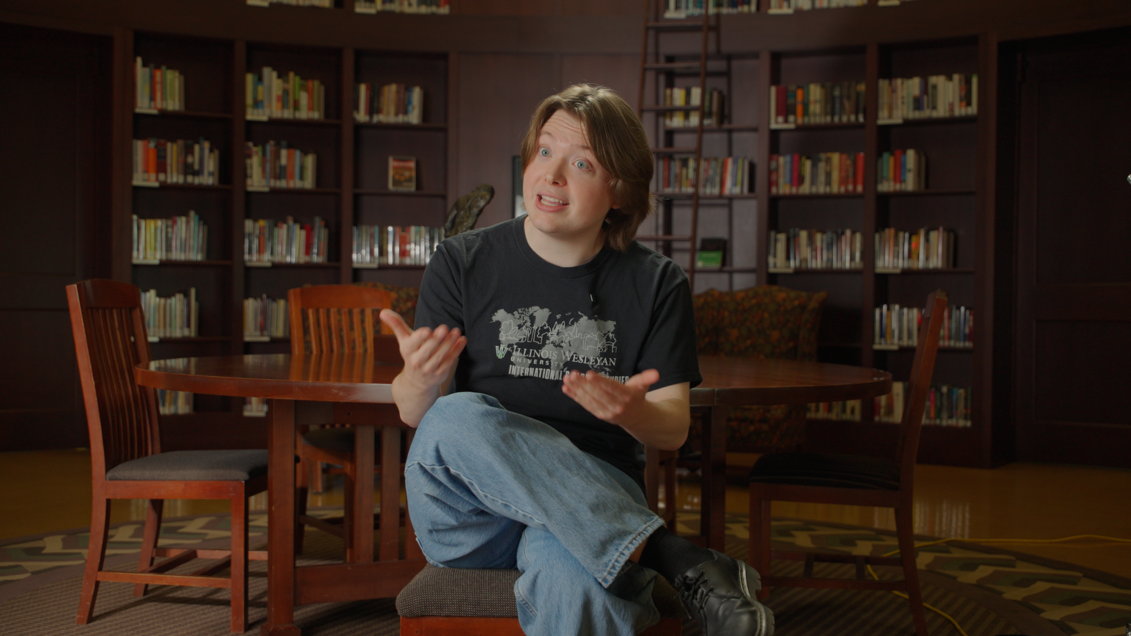 A student sits in a library at Illinois Wesleyan University telling a story