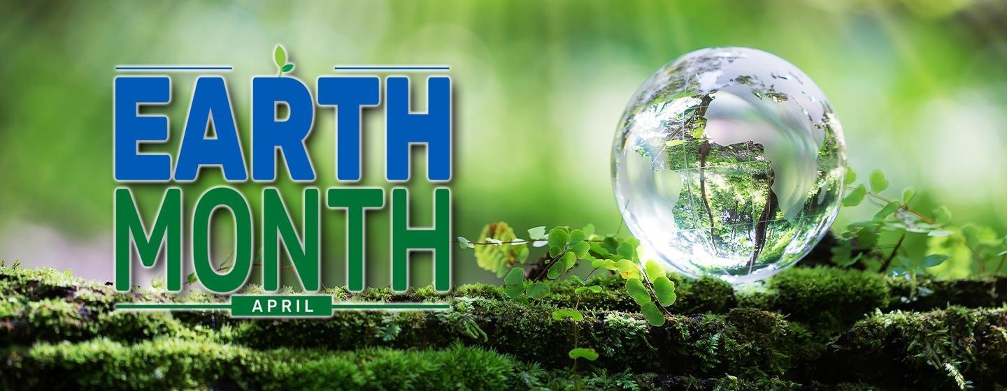 ext: Earth Month | April, over a green blurred background with a small glass globe sitting on a moss covered log.