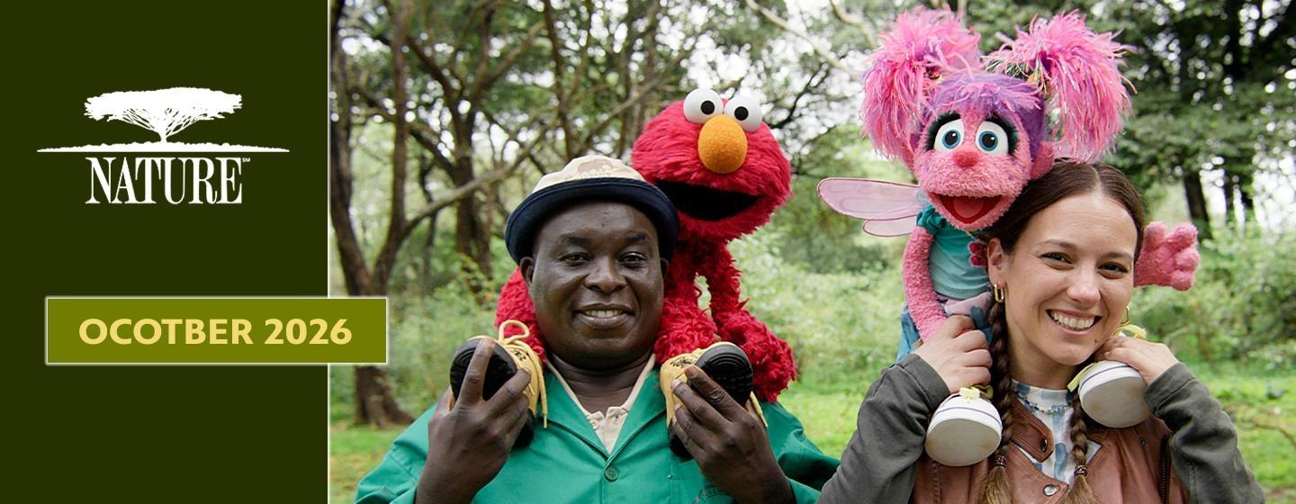 Nature October 2026 banner featuring Elmo and Abby Cadabby with two smiling people in a wooded setting.