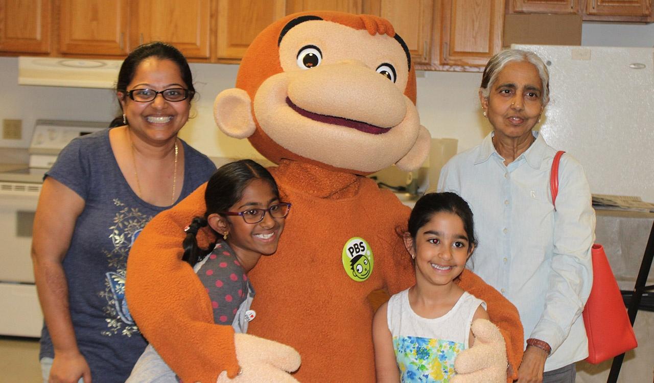 Family mingling with Curious George in the kitchen before 2017 Writers’ Contest Event