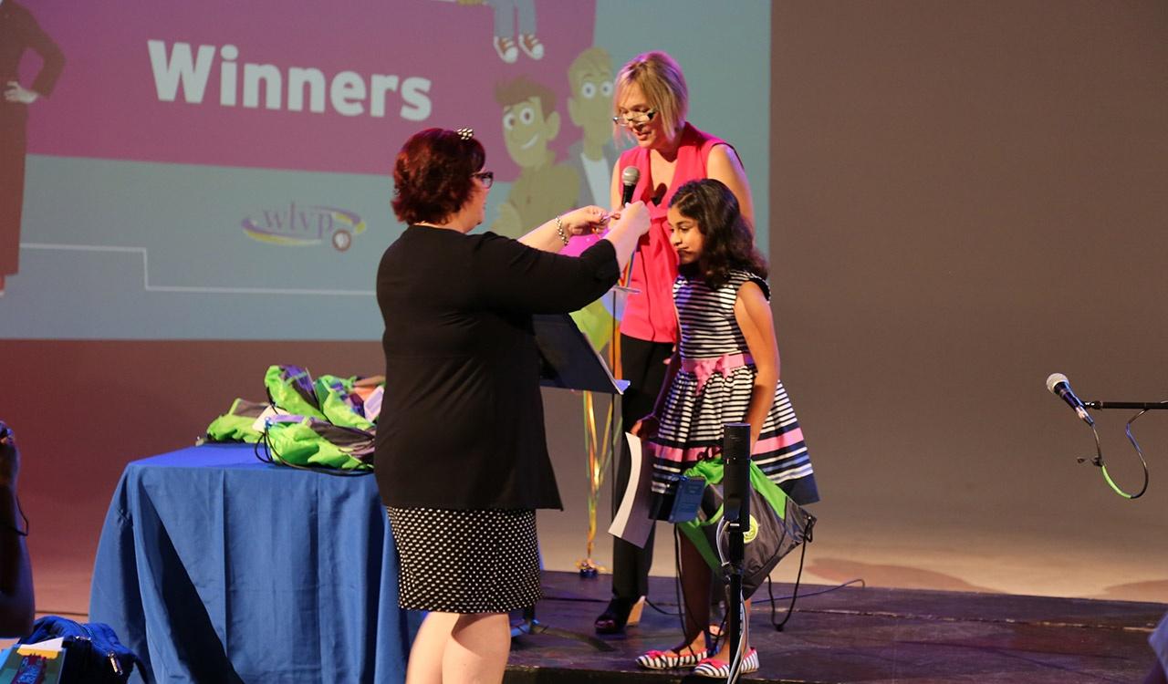 Julie giving a winner her medal at 2017 Writers contest