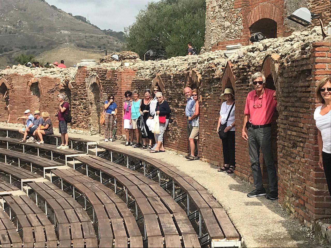 Travelers standing in Statue Coves in Ancient Greek Theater
