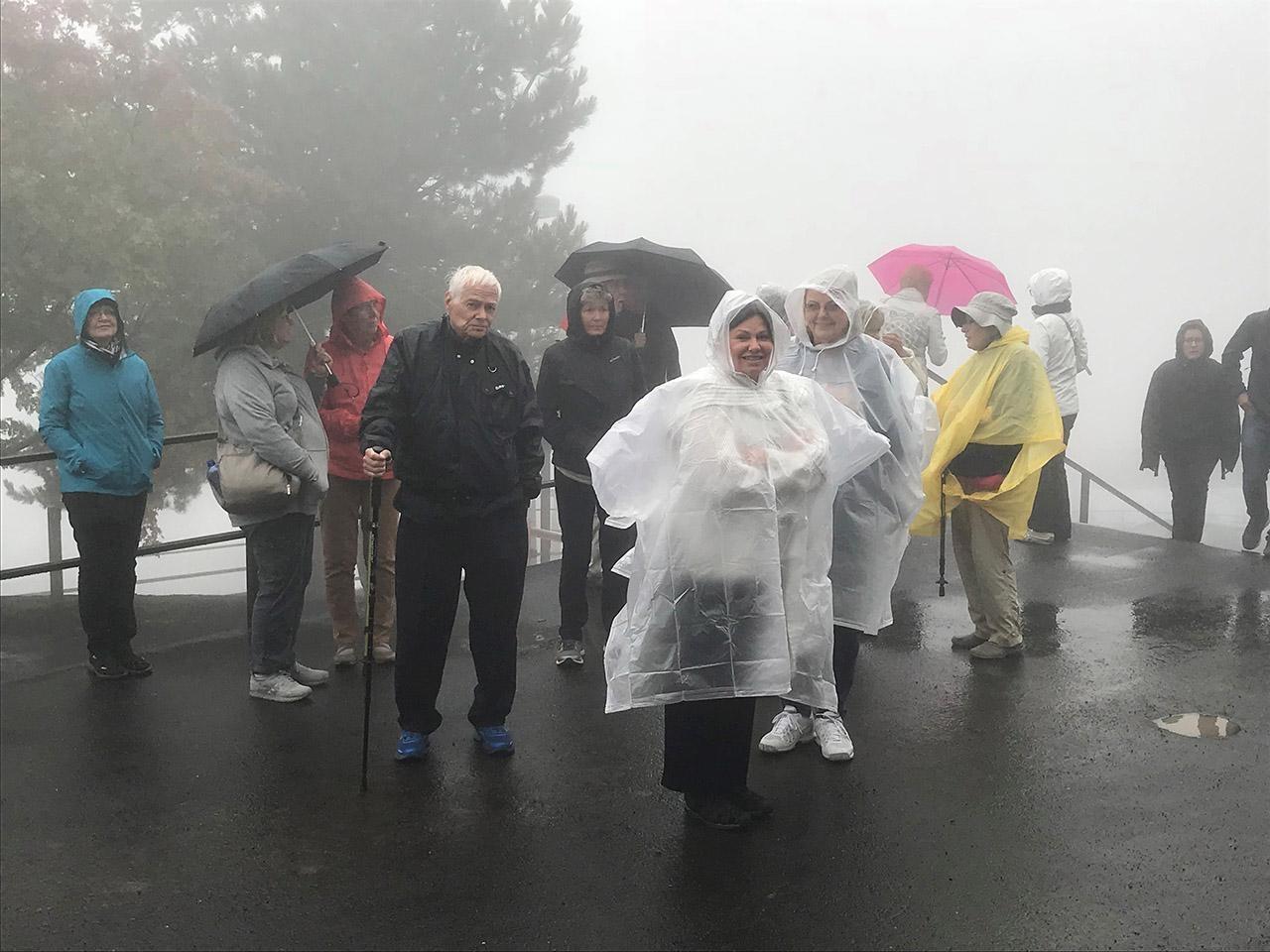 Group of travels in rain gear standing in the fog