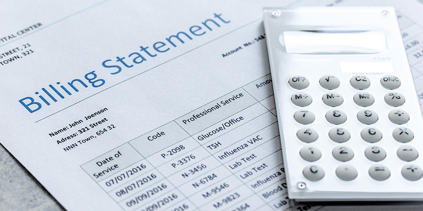 A white calculator sits on top of a paper billing statement