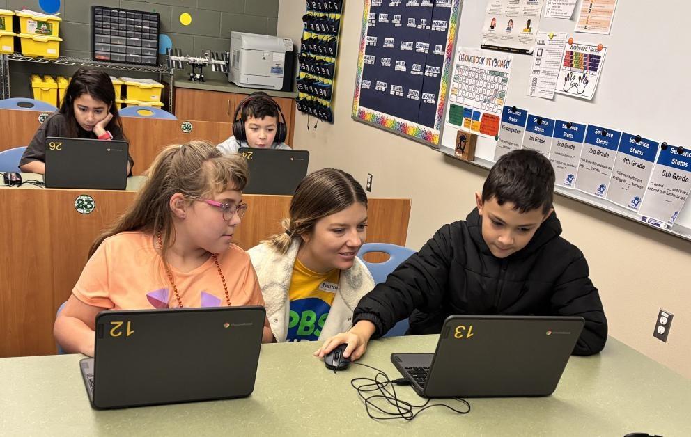 Kids looking at their computer screens as an education specialist looks on