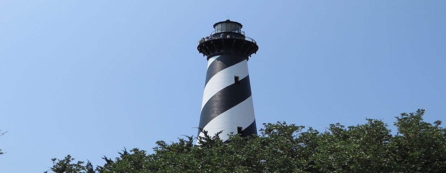 cape hatteras black and white striped lighthouse nc from far below with trees at bottom