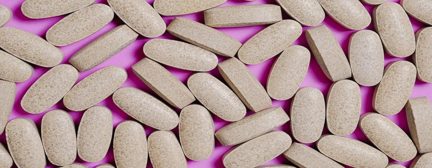 beige blank pills on pink background table