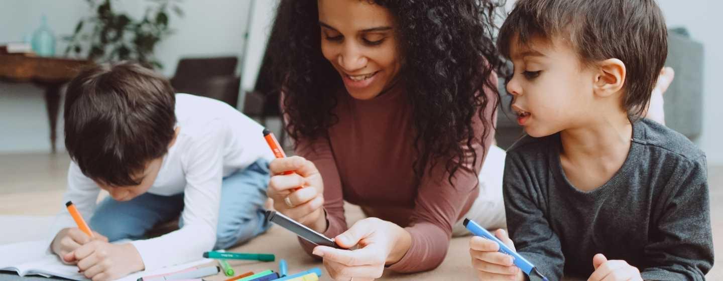 Two children coloring on the floor with their parent.