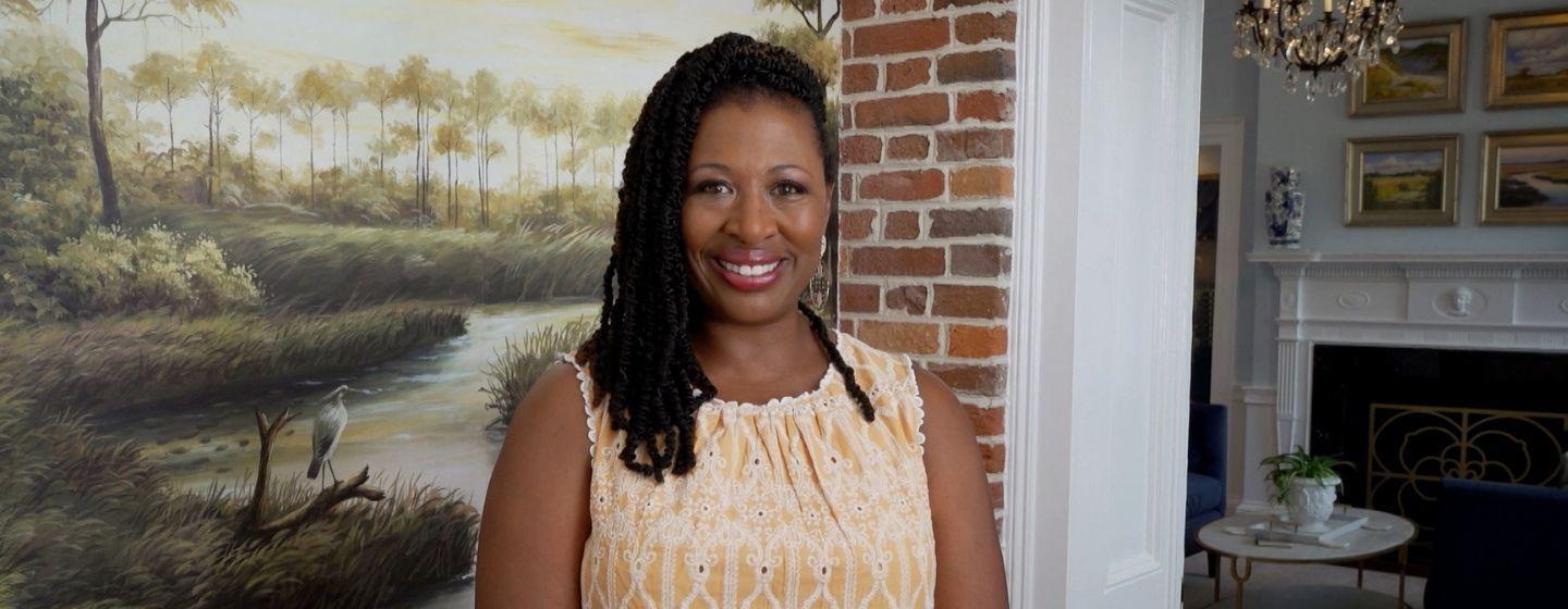 Deborah Holt Noel in from of a mural inside a historic building.