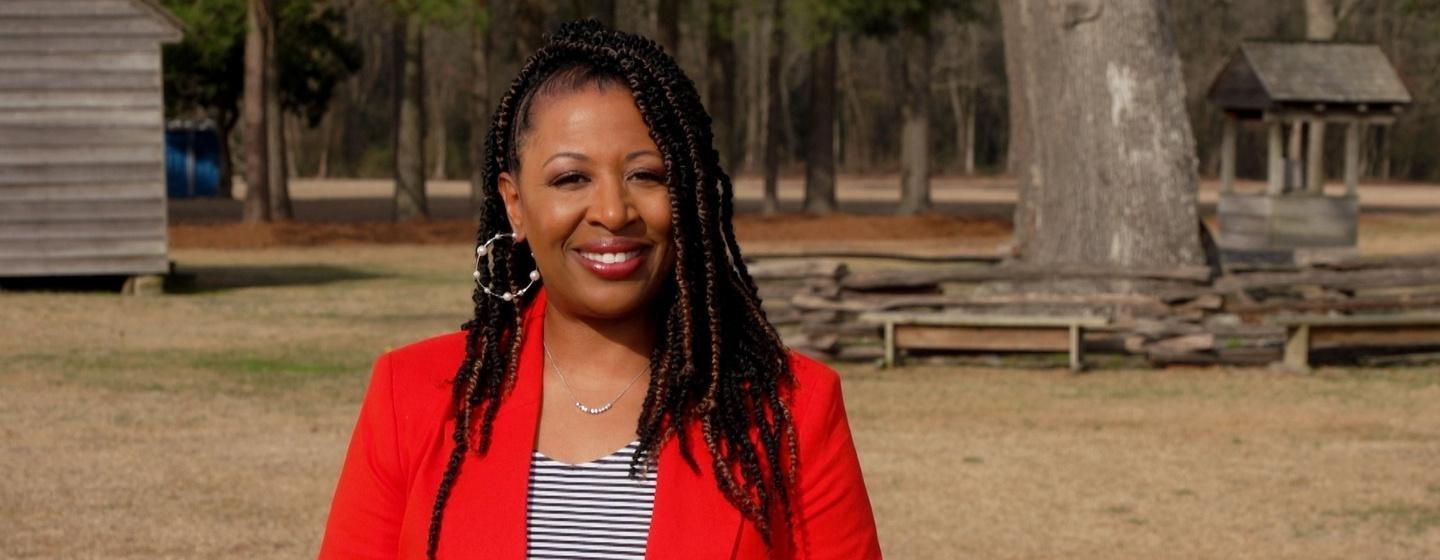 Host of NC Weekend Deborah Holt Noel in front of a wooded area.