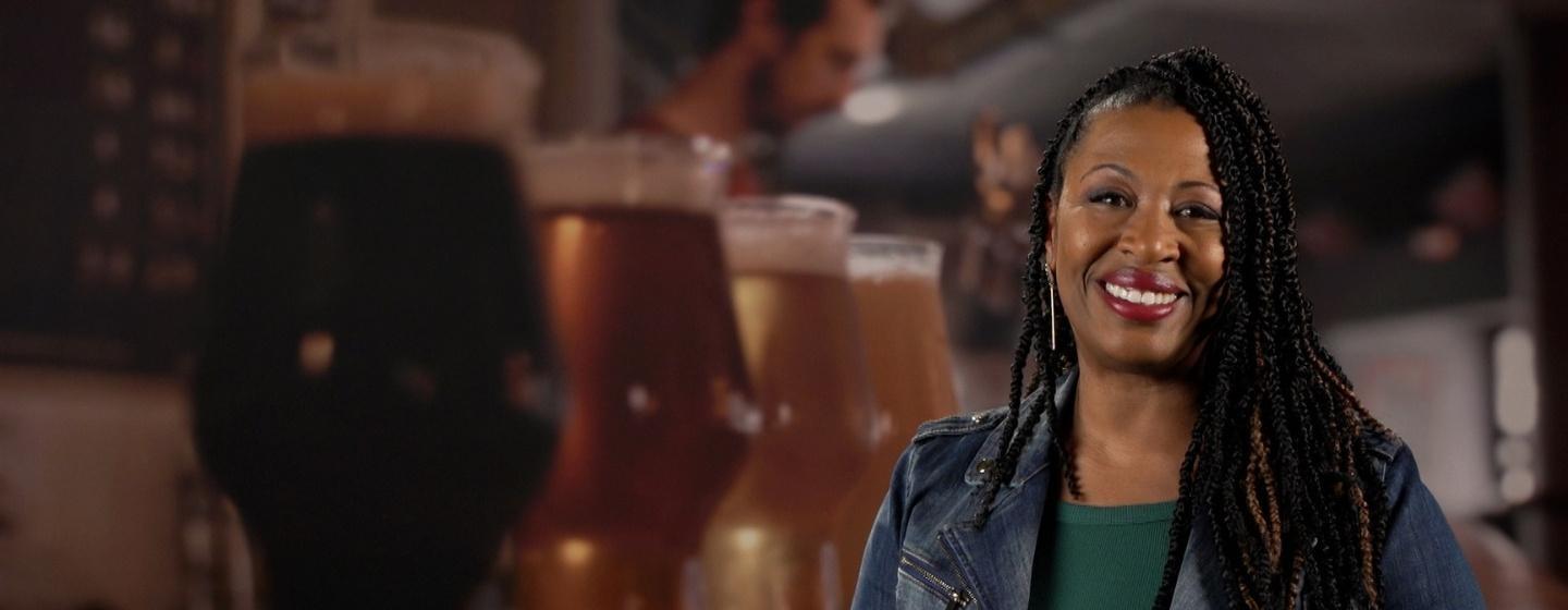 Host of NC Weekend, Deborah Holt Noel in front of a green screen of a beer flight.