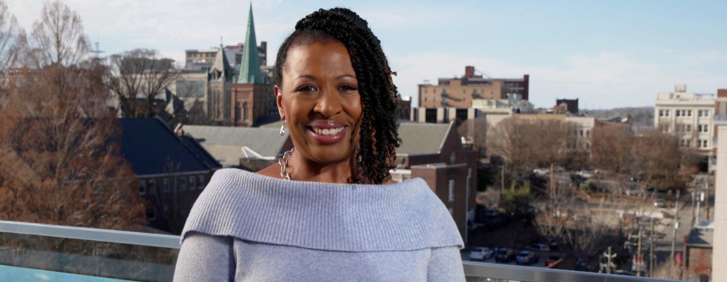 Host of NC Weekend Deborah Holt Noel with Asheville behind her.