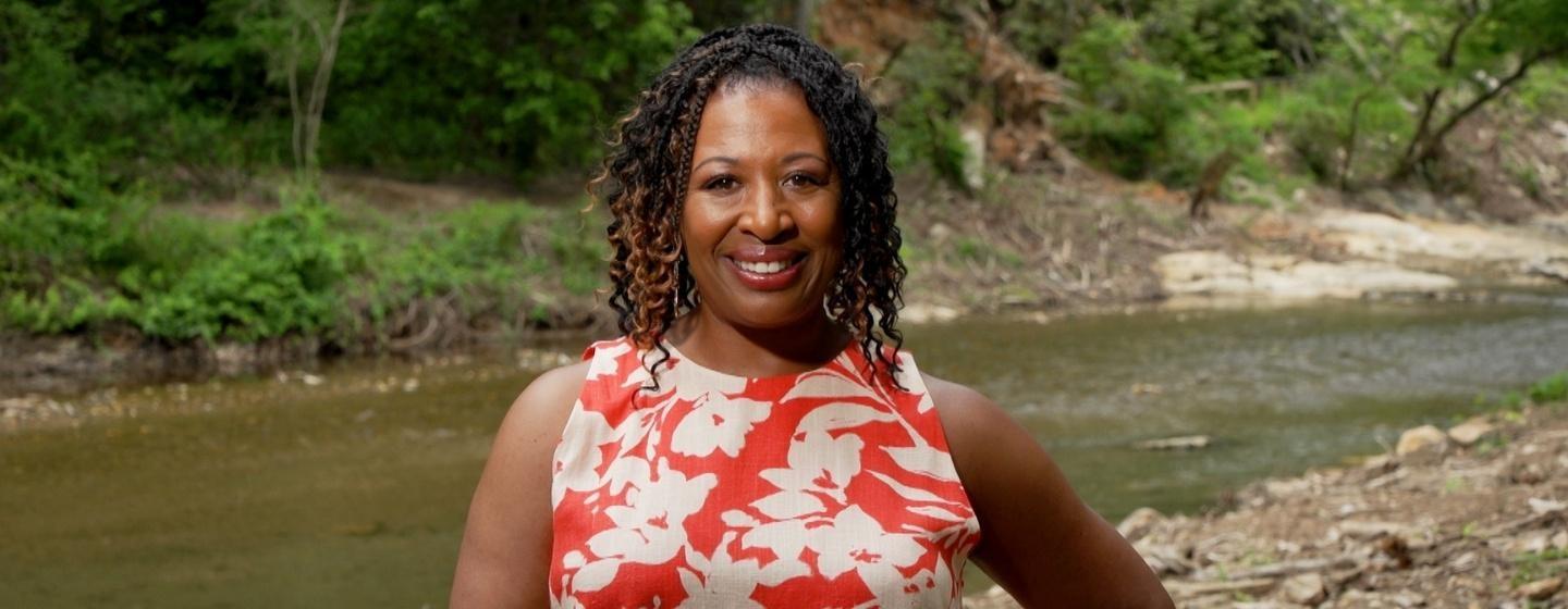 Host of NC Weekend, Deborah Holt Noel standing in front of a creek.