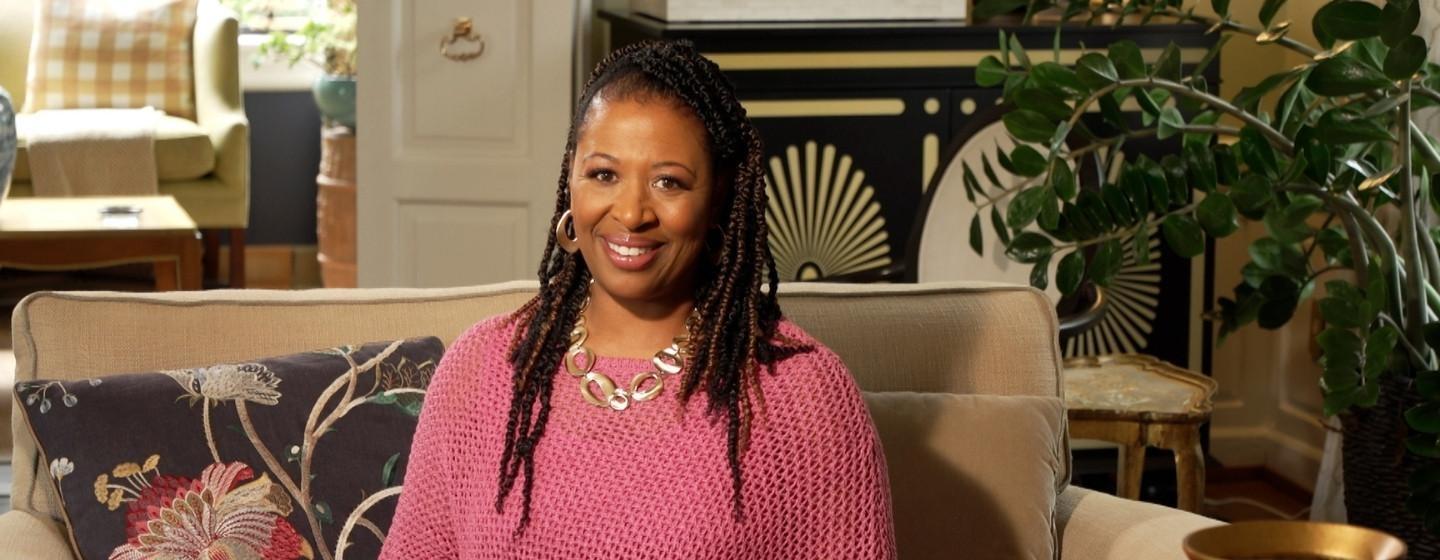 Host of NC Weekend, Deborah Holt Noel on a couch in a hotel lobby.