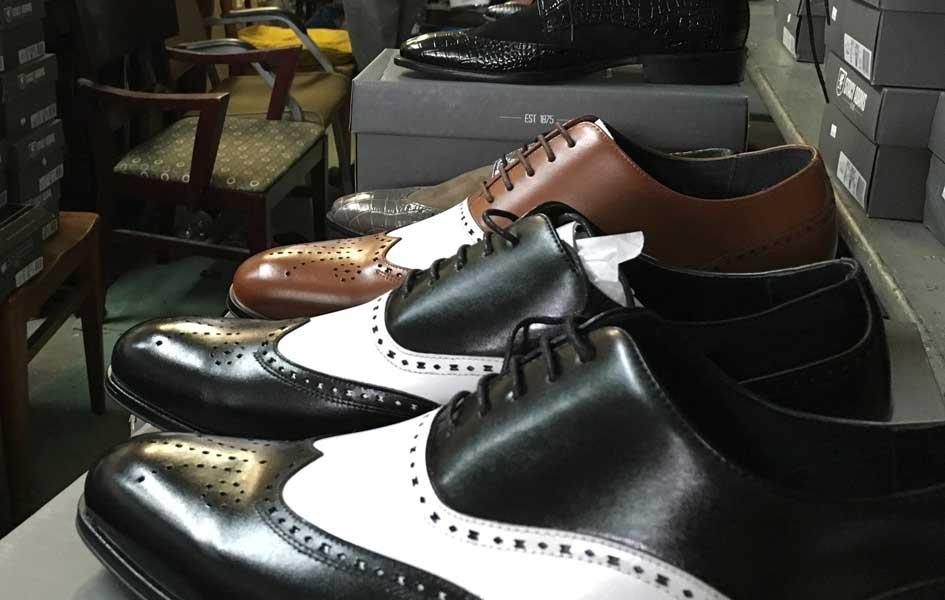 black, white and brown mens shoes lined up in a row and sitting on display stand