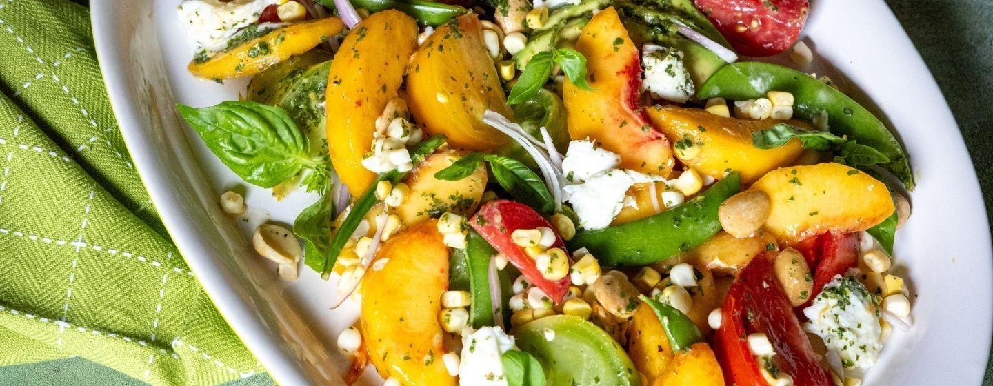 Fresh Peach and Summer Vegetable Salad in a white ceramic dish.