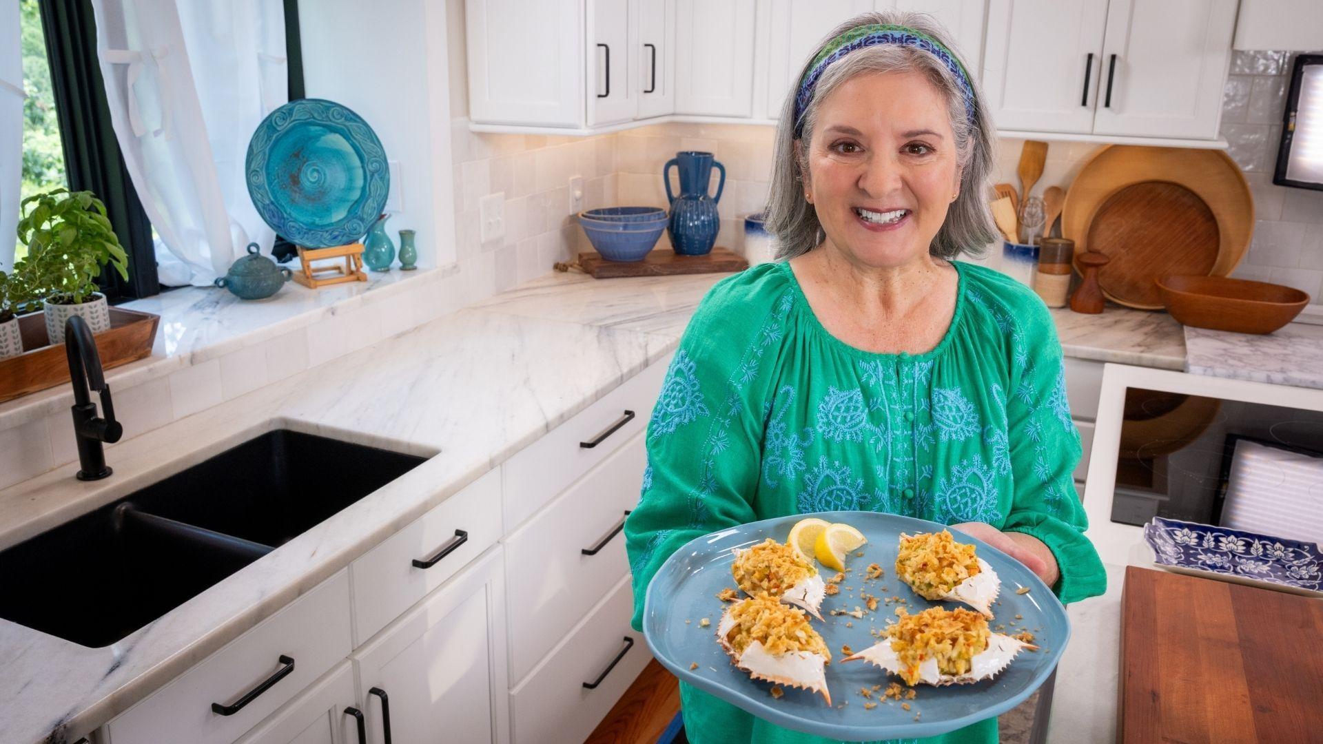 Sheri Castle holding up a plate of deviled crabs.