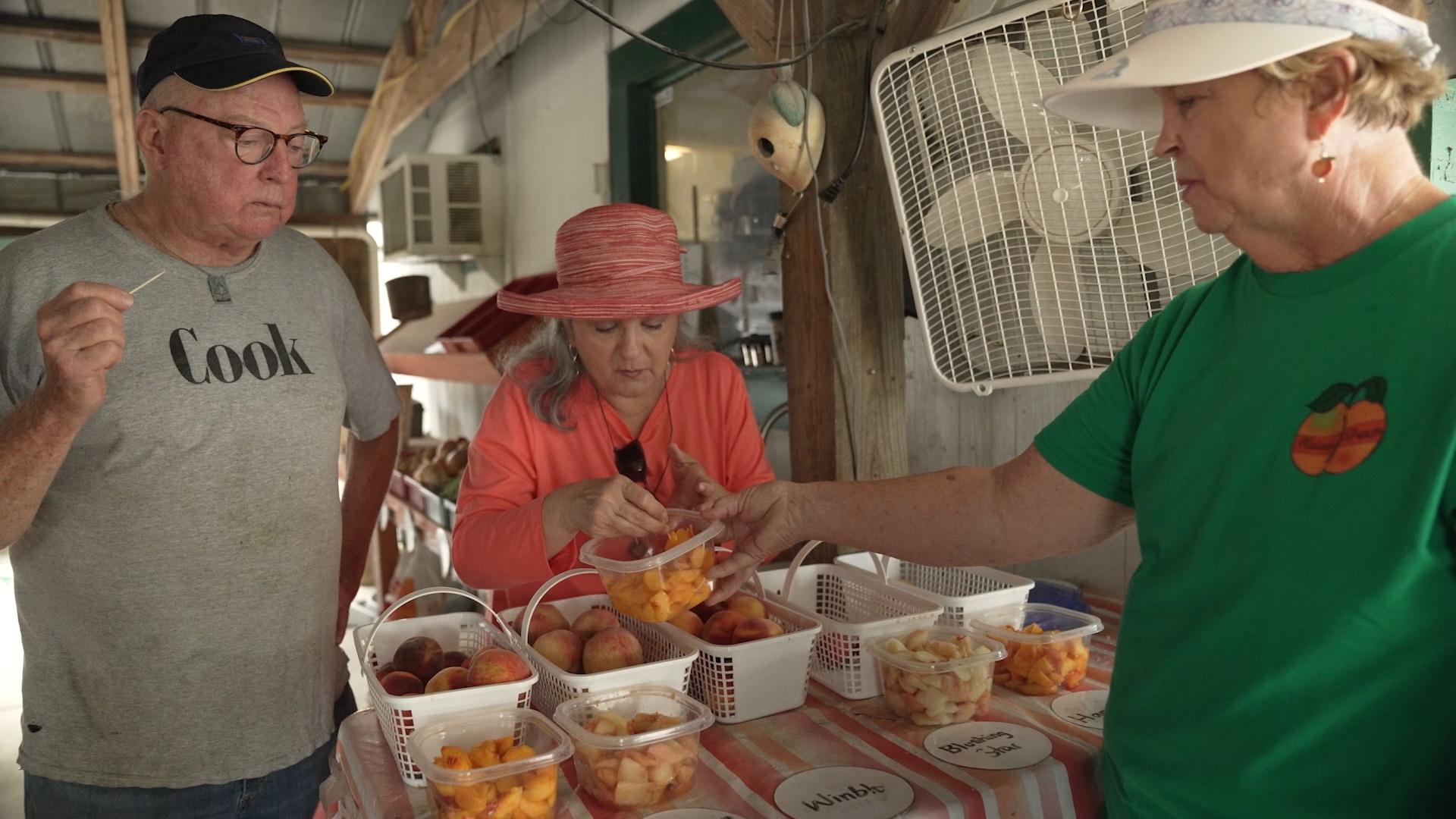 Bill Smith and Sheri Castle tasting different varieties of peaches with another lady.