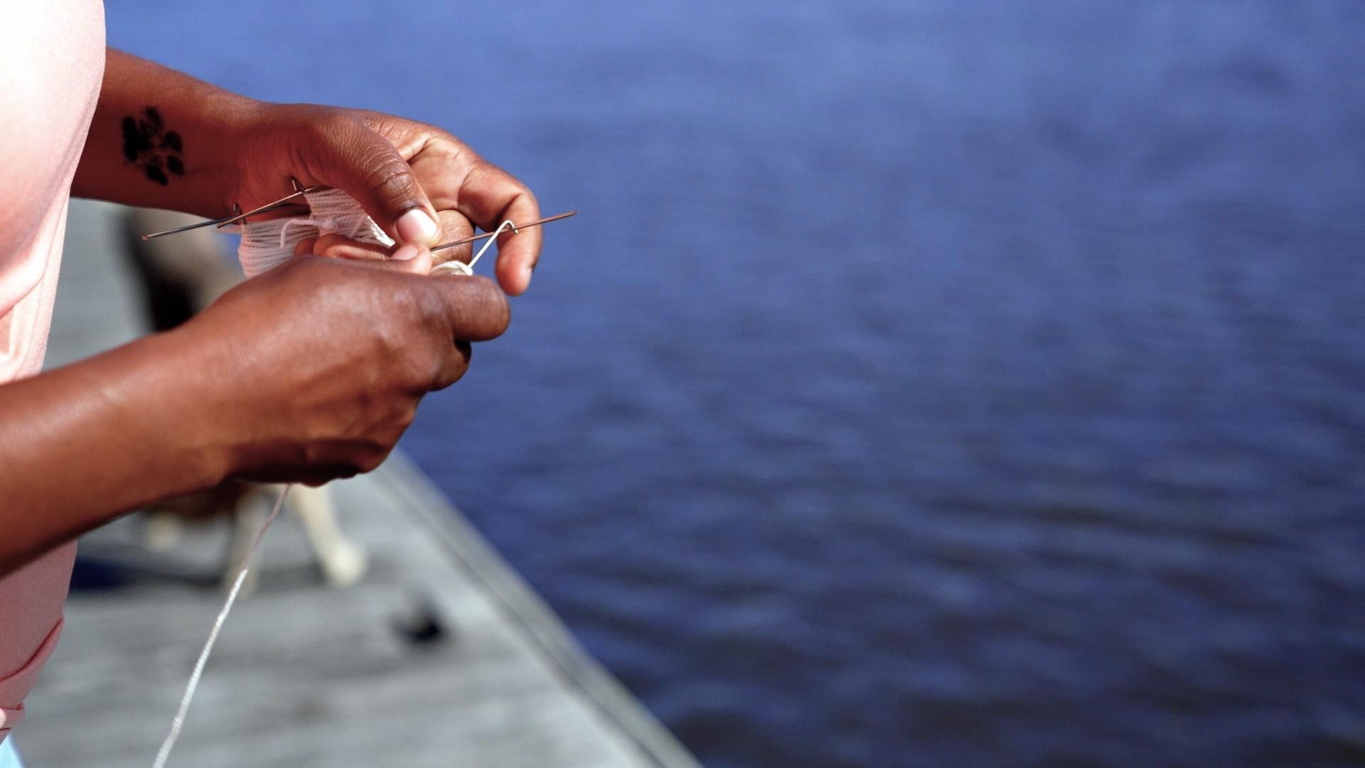 The hands of Tia Clark tying some knots to prepare for crabbing.