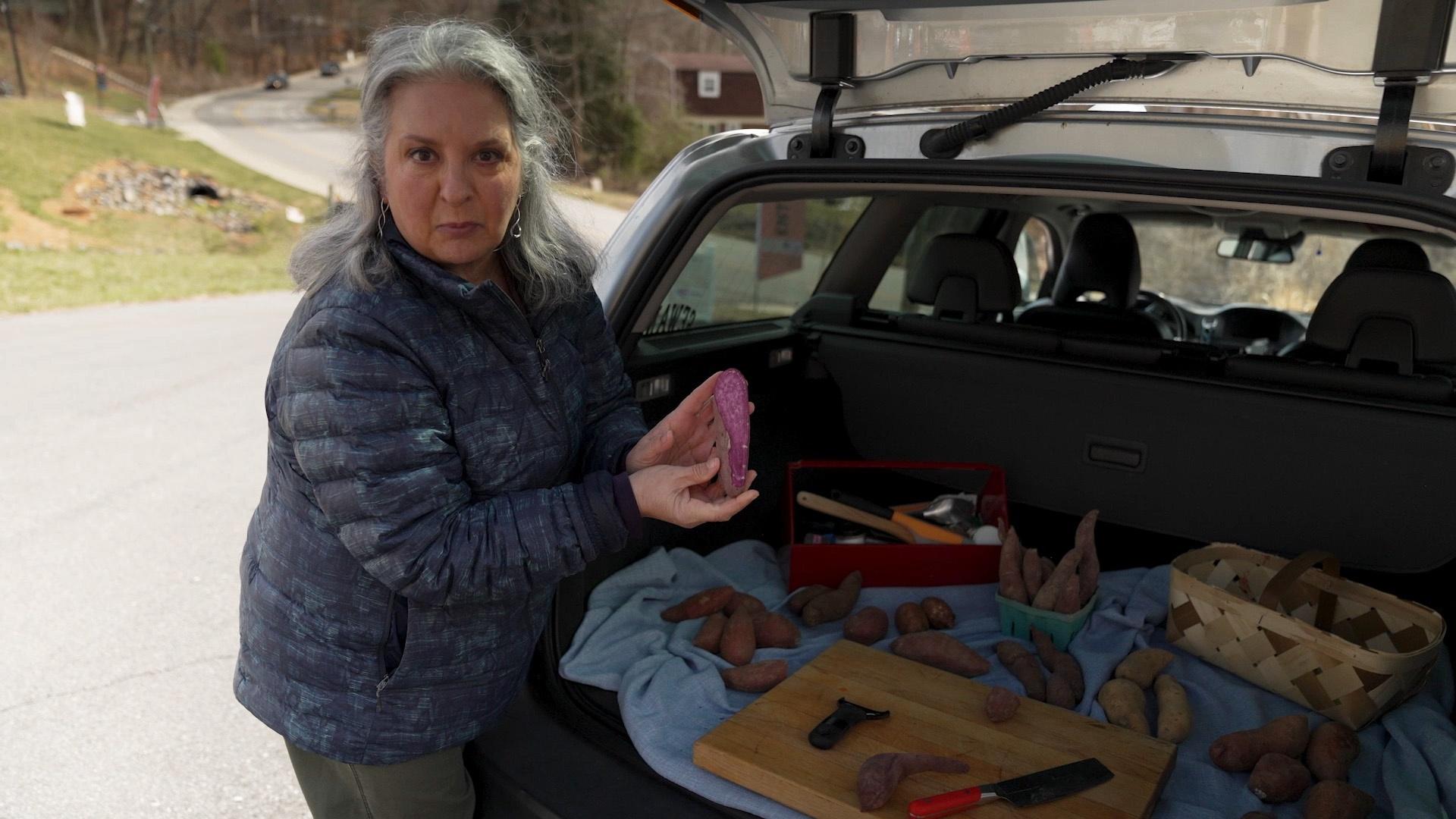 Sheri holding up a purple sweet potato.