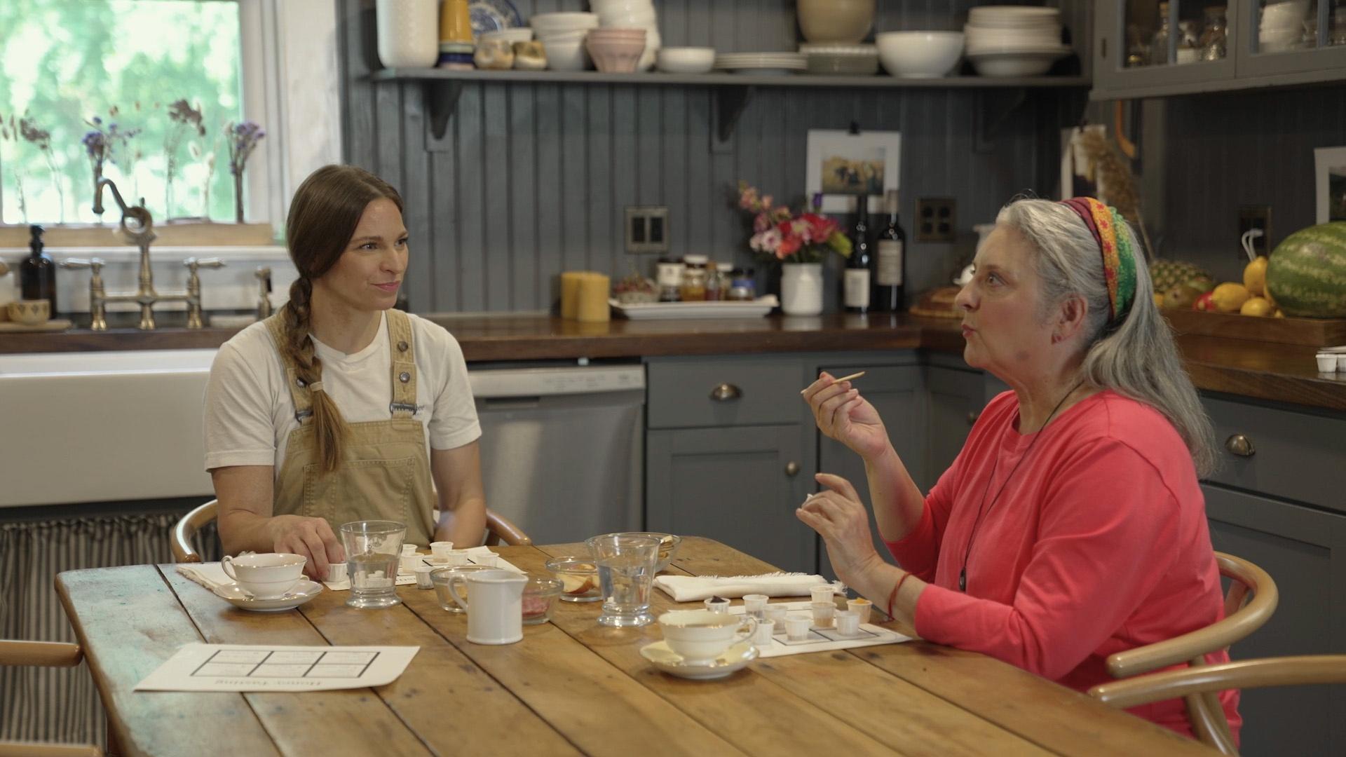 Mary Garrison and Sheri Castle sitting at a table tasting honey.