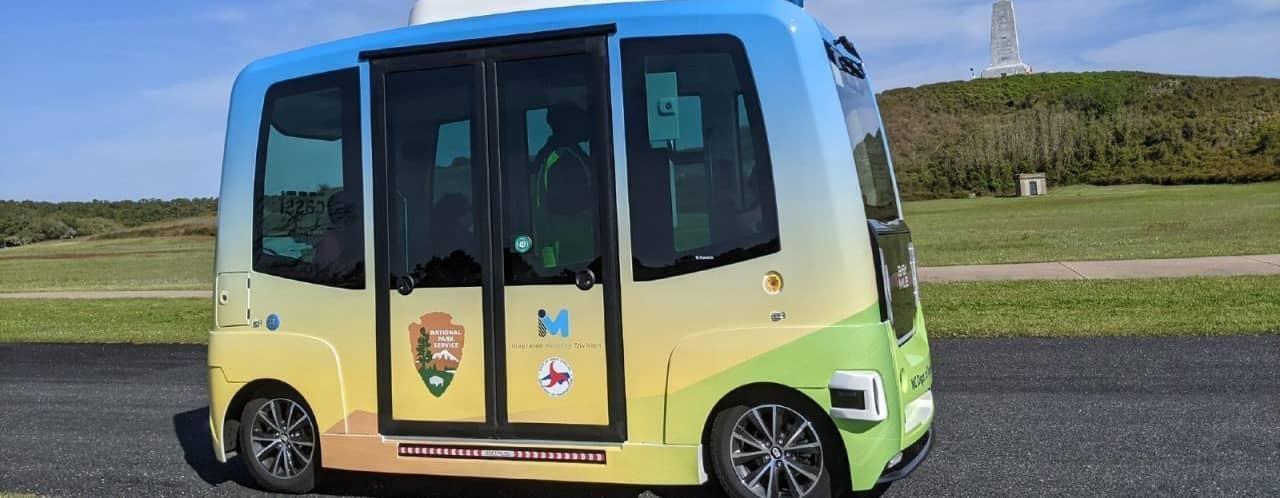 autonomous bus driving self driving bus car vehicle at wright brothers memorial road grass and trees background outer banks
