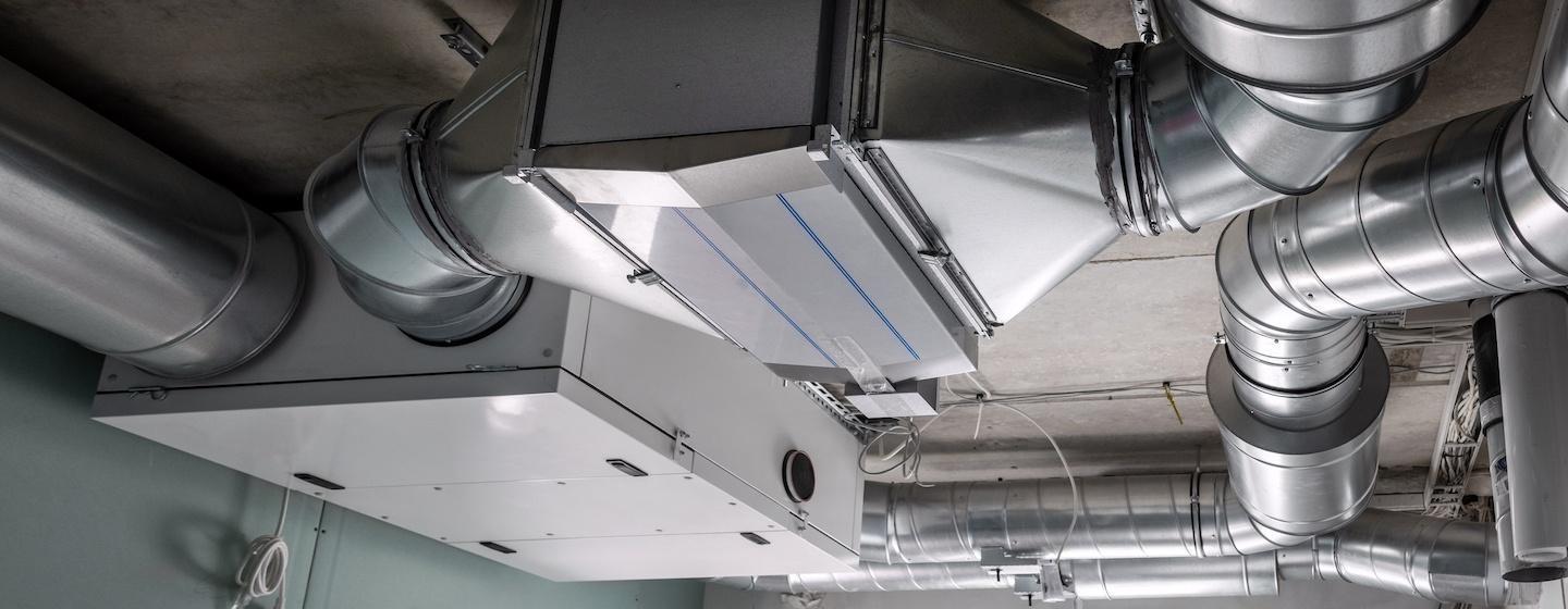 HVAC pipes and unit indoors on ceiling of building