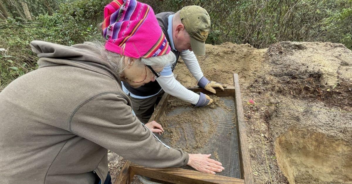 Two people look at treasures sifted through a screen.