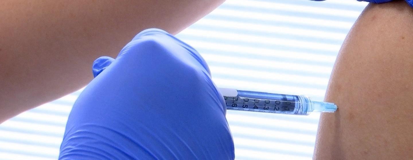 vaccine shot being administed into shoulder by gloved hand doctor nurse covid