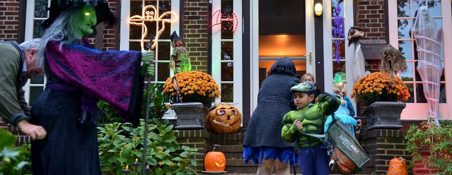kid trick or treating in hulk costume at house with witch decoration