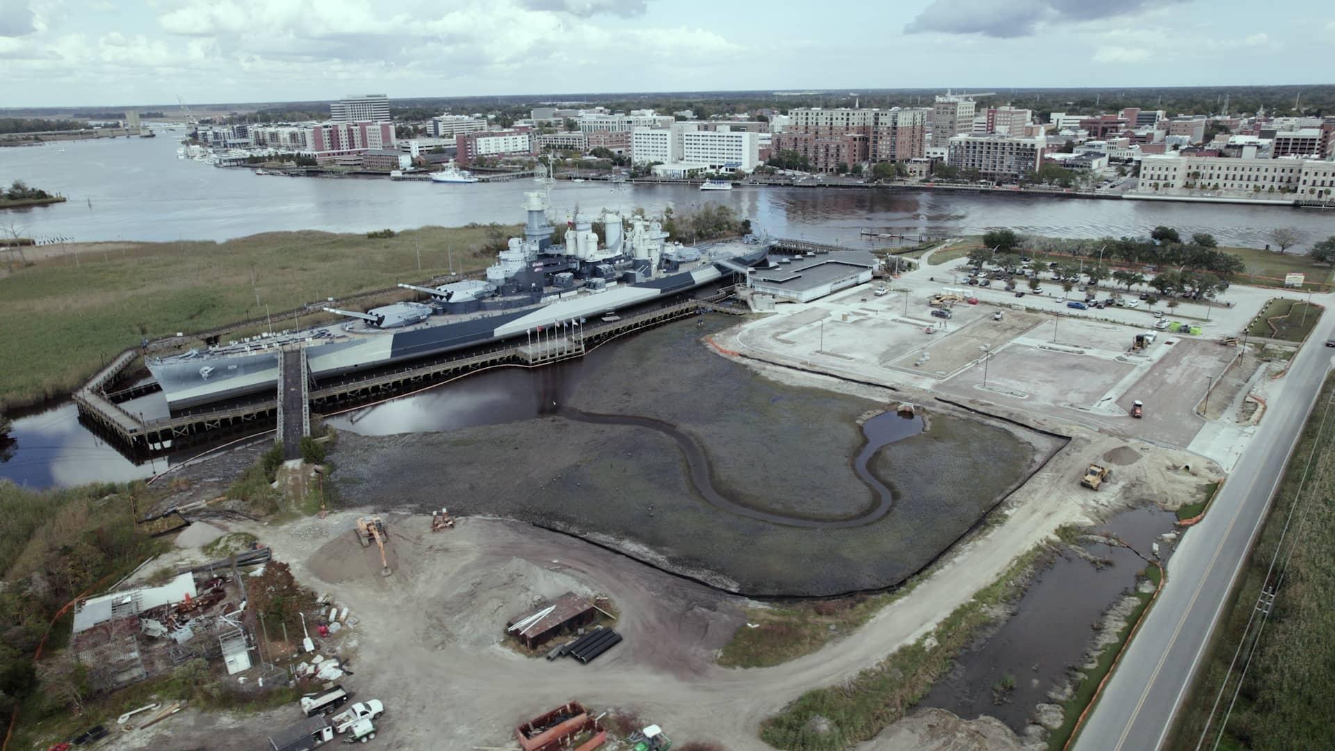 The ship is berthed directly across from downtown Wilmington and is adjacent to where the Northeast Cape Fear River and Cape Fear River meet. This image is during low tide, so the infrastructure of the tidal marsh that’s part of the Living with Water project is visible.