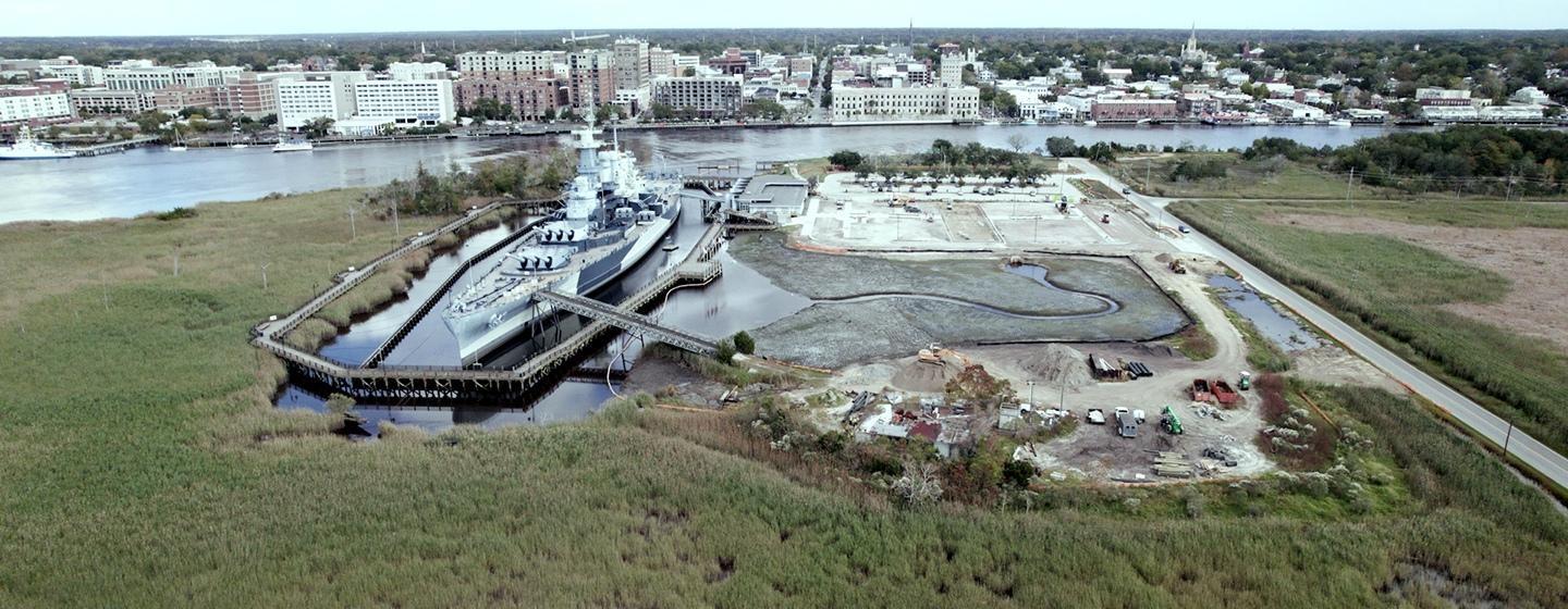 The ship is berthed directly across from downtown Wilmington and is adjacent to where the Northeast Cape Fear River and Cape Fear River meet. This image is during low tide, so the infrastructure of the tidal marsh that’s part of the Living with Water project is visible.