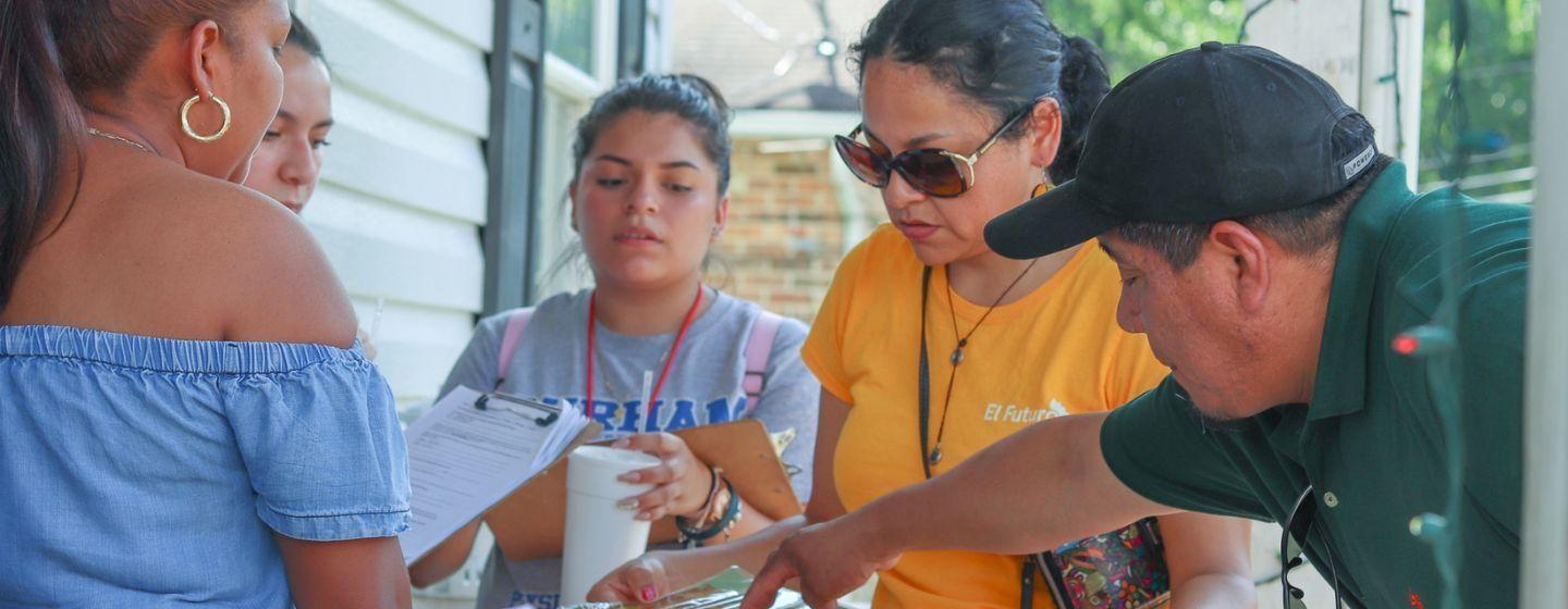 Group of muralists looking at the graphic/plan for a Durham mural.