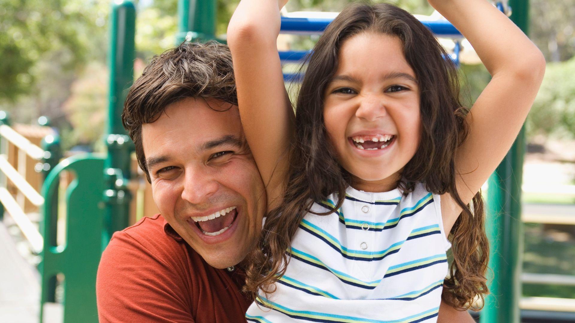 Father and daughter on a playground outside.
