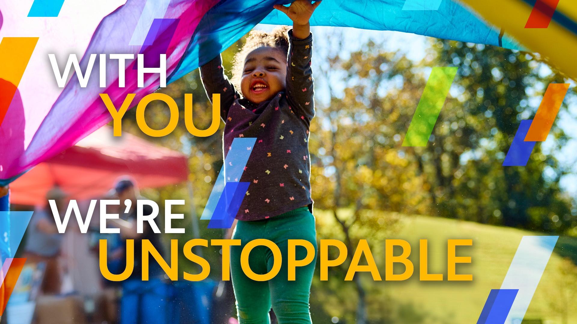 The text "WITH YOU WE'RE UNSTOPPABLE" over an image of a young Black child waving a colorful sheet around outside.