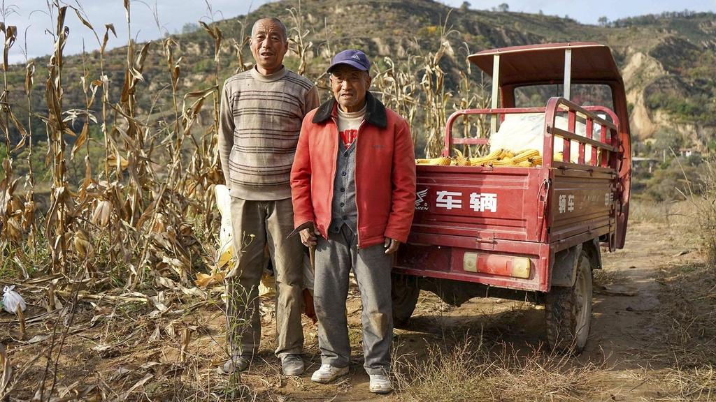 Farmers standing in front of a cornfield.