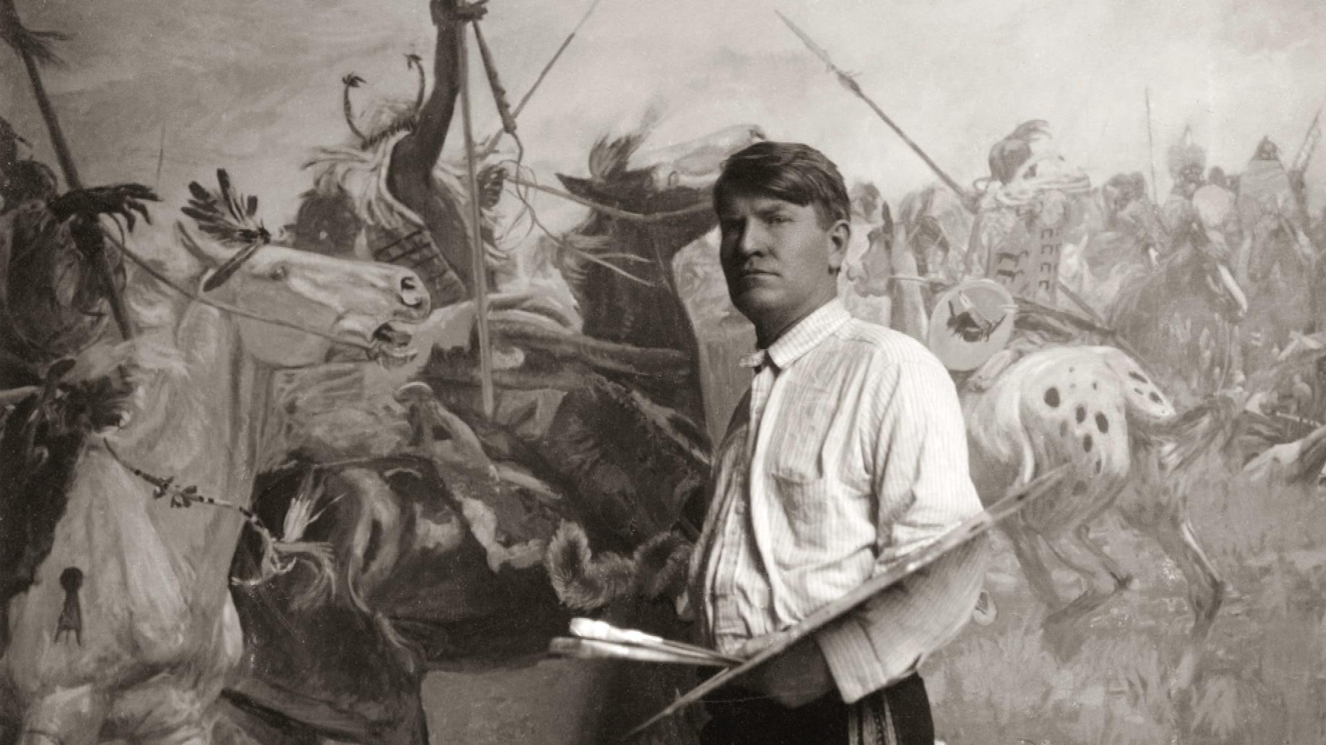 Black and white image of Charlie Russell standing in front of a painting.