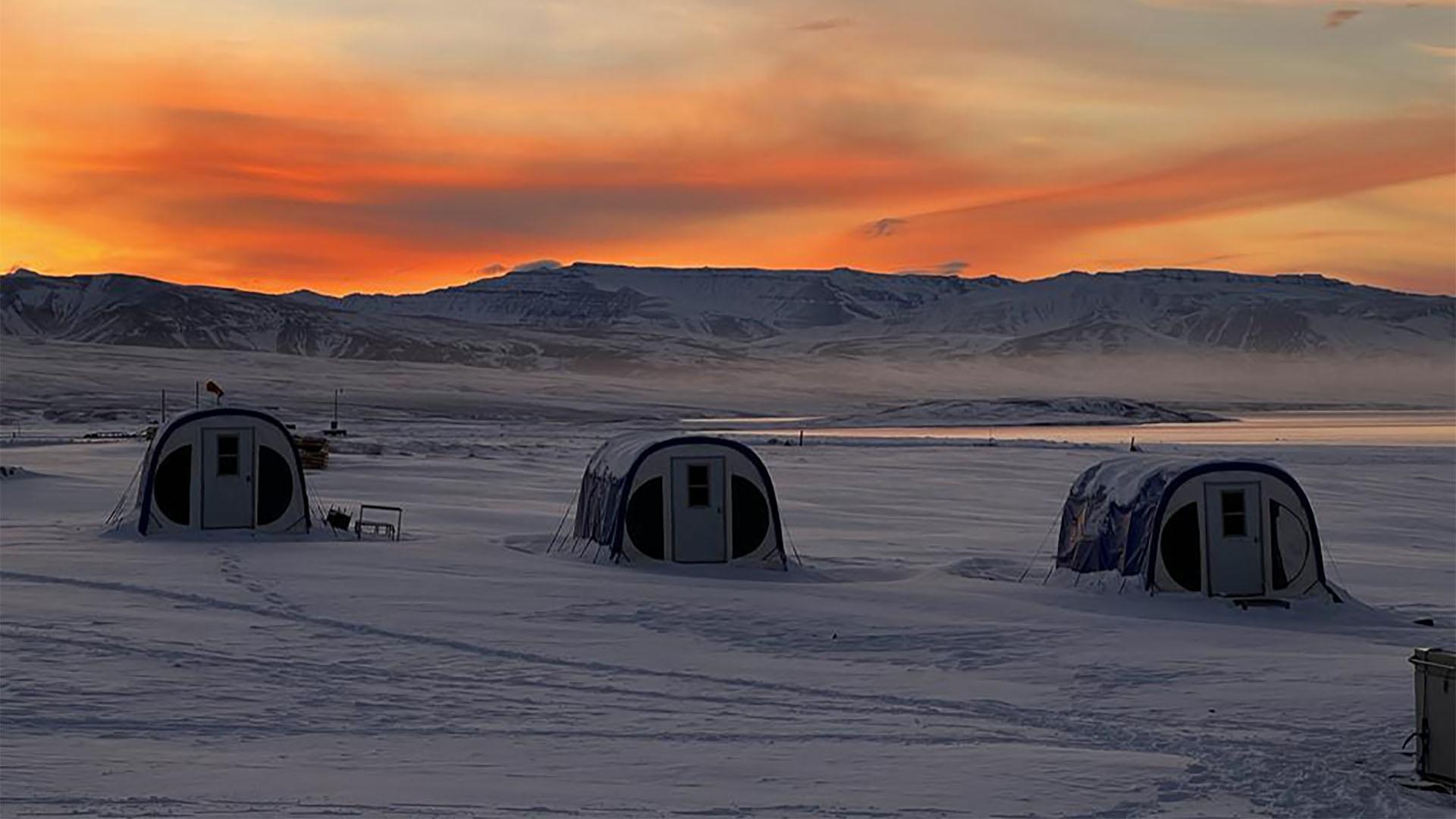 Image of a sunset over three tents.