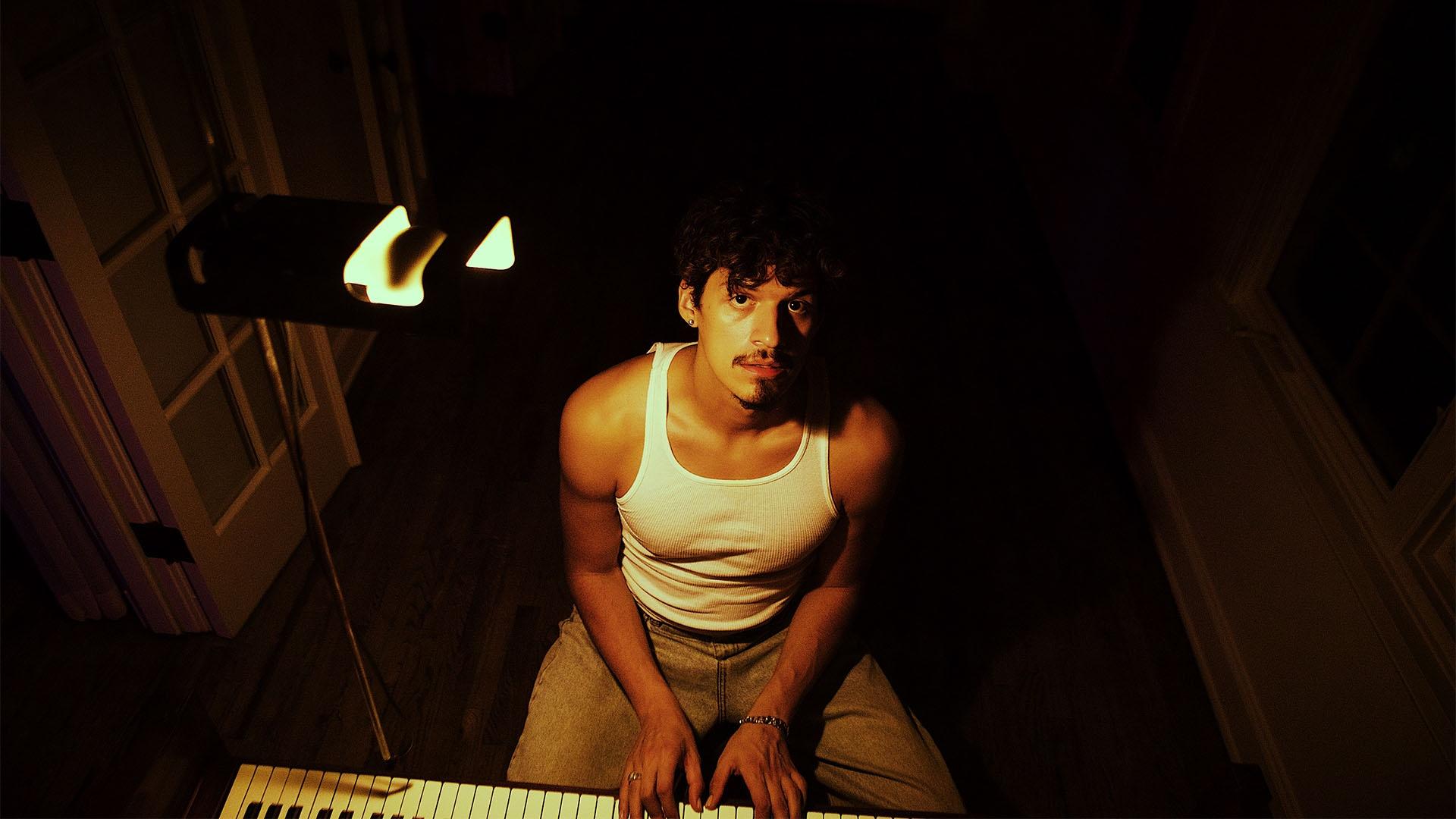 Portrait image of Omar Apollo sitting at piano