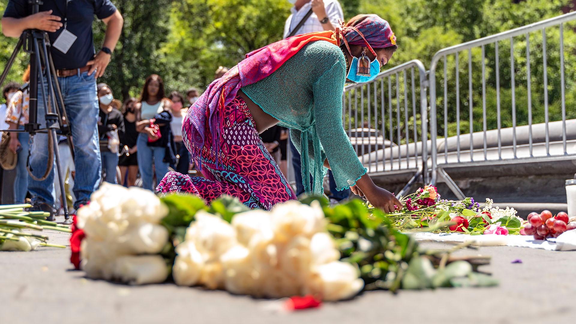 A protester lies a bouquet of flowers at the site of a vigil for slain activist Oluwatoyin Salau.
